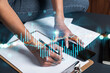 © VideoFlow - Businesswoman taking notes using smart-phone. Financial forex graph and chart hologram double exposure.