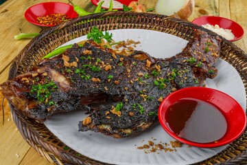 Wall Mural - Big piece of roasted meat with seasonings served on a plate and a small bowl of sauce