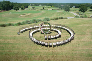 Wall Mural - Unique round spiral chair pattern wedding ceremony setting at rolling hills countryside with brown chiavari chairs and white cushions