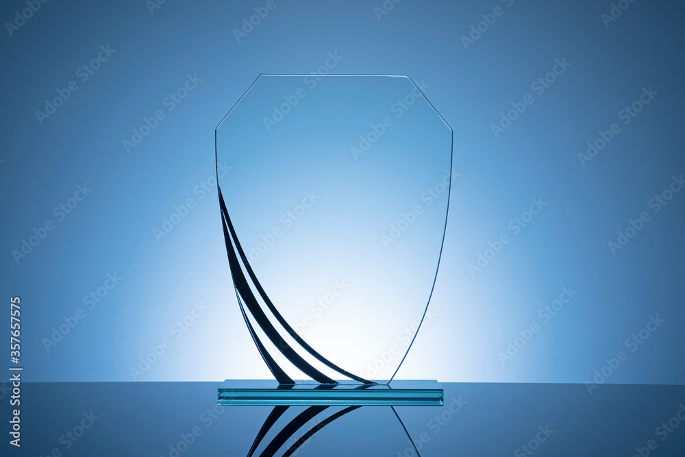Elegant blank glass shield trophy on dark blue - obrazy, fototapety, plakaty 