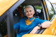 © Anatoliy Karlyuk - Attractive successful retired blonde woman wearing blue shirt and wrist watch sitting comfortably in her new yellow car, resting elbow on open window, having confident happy facial expression