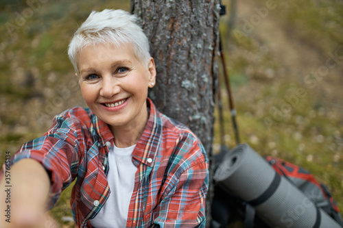 Fotografía Portrait of happy attractive middle aged woman with blonde hair sitting under pi