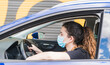 © Tomaspf_ - New normal. Female driver with a medical face mask driving a car with a passenger. Health protection. Family in the car protected by a mask safety and pandemic concept. Coronavirus. Social distance.