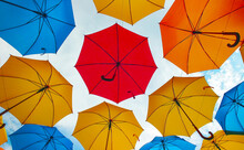 Colorful Umbrellas Hanging Overhead Over A Blue Sky