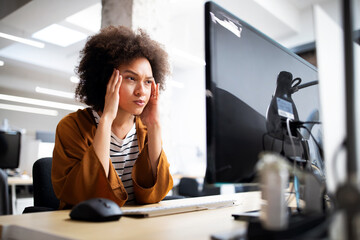 Overworked and frustrated young woman in front of computer in office