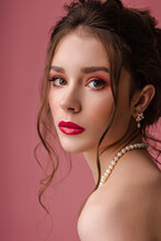 Beauty Portrait Of Young Beautiful Elegant Model, Woman With Red Color Eyes, Lips Makeup, Wearing Trendy Pearl Earrings, Necklace, Posing On Pink Background. Jewelry Advertising Conception