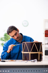 Young male repairman repairing drum