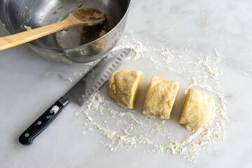 Hungarian Zserbo Szelet Dough: Kneaded pastry dough cut into three pieces with a white marble background