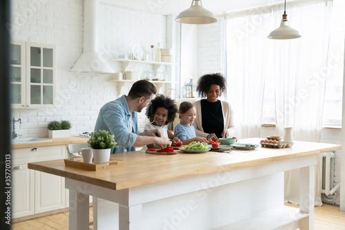 Fotografía Happy mixed race multinational family with daughters prepare vegetable organic f