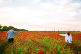 Fototapeta Kuchnia - Loving couple walking on the poppy field. Summertime. Enjoying time together. The concept of youth, love and lifestyle.