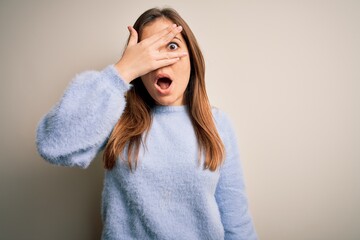 Sticker - Beautiful young woman wearing casual winter sweater standing over isolated background peeking in shock covering face and eyes with hand, looking through fingers with embarrassed expression.