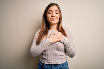 Sticker - Beautiful young woman standing casual over isolated background smiling with hands on chest with closed eyes and grateful gesture on face. Health concept.