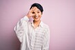 © Krakenimages.com - Young beautiful asian girl wearing casual shirt standing over isolated pink background doing ok gesture with hand smiling, eye looking through fingers with happy face.
