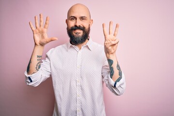 Wall Mural - Handsome bald man with beard wearing elegant shirt over isolated pink background showing and pointing up with fingers number eight while smiling confident and happy.