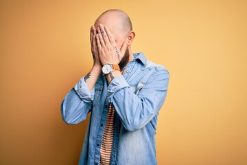 Sticker - Handsome bald man with beard wearing casual denim jacket and striped t-shirt with sad expression covering face with hands while crying. Depression concept.