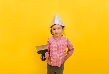 a little girl Builder in a paper hat with a metal trowel on a yellow isolated background with space for text