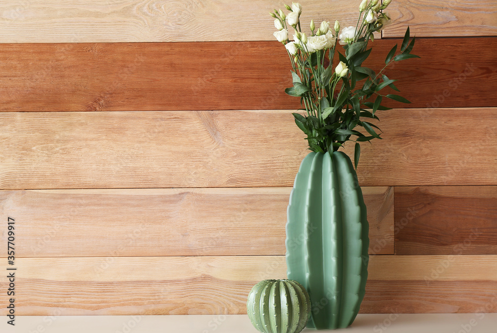 Vases with beautiful flowers on table near wooden wall