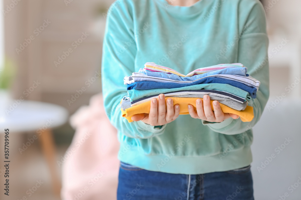 Woman with stack of clean clothes at home, closeup