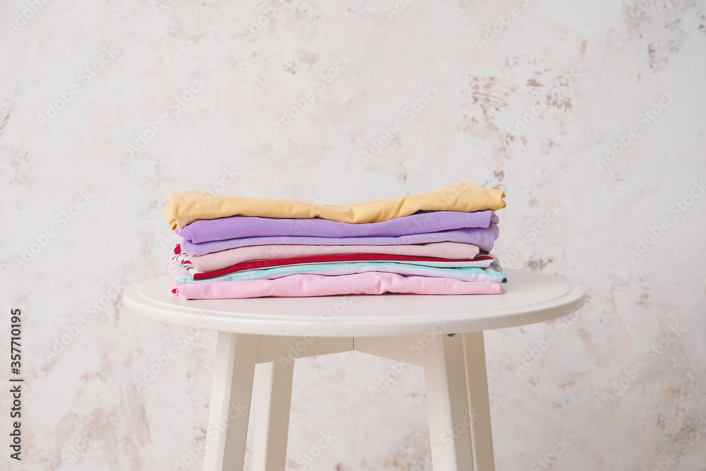 Stack of clean clothes on table against light background