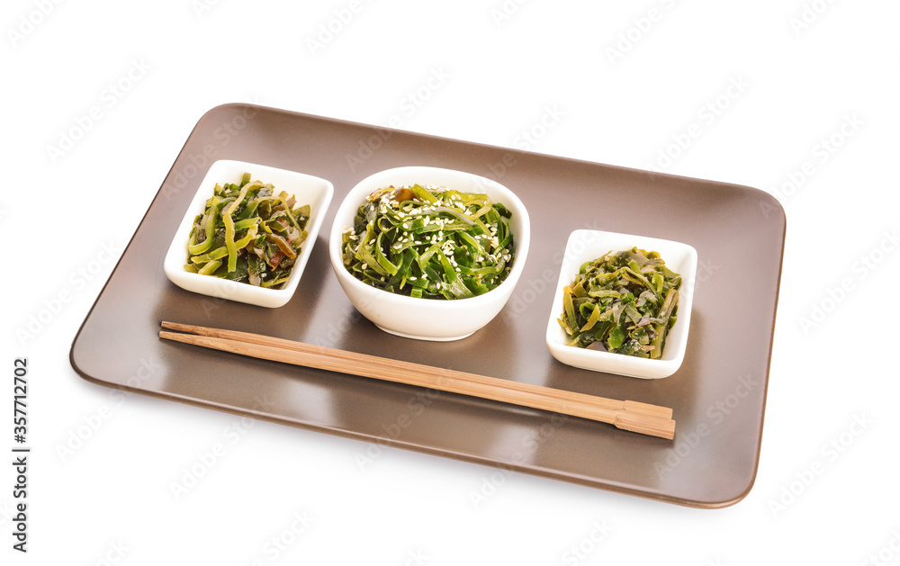 Bowls with tasty seaweed and chopsticks on white background