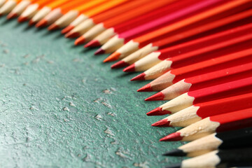 Many colorful pencils on green background