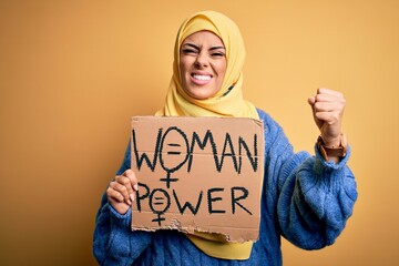 Wall Mural - Young beautiful arab woman wearing islamic hijab holding banner with women power message annoyed and frustrated shouting with anger, crazy and yelling with raised hand, anger concept