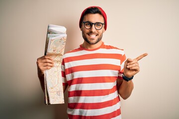 Canvas Print - Young handsome tourist man on vacation wearing glasses holding city map very happy pointing with hand and finger to the side