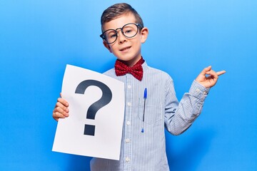 Poster - Cute blond kid wearing nerd bow tie and glasses holding question mark smiling happy pointing with hand and finger to the side