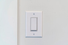 Electrical Rocker Light Switch With Flat Broad Lever On White Interior Wall