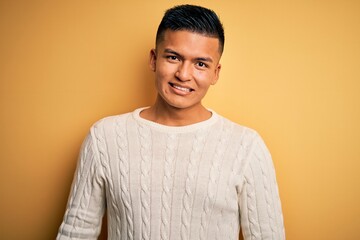 Young handsome latin man wearing white casual sweater over yellow background with a happy and cool smile on face. Lucky person.