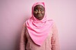 © Krakenimages.com - Young african american plus size woman wearing muslim hijab over isolated pink background puffing cheeks with funny face. Mouth inflated with air, crazy expression.