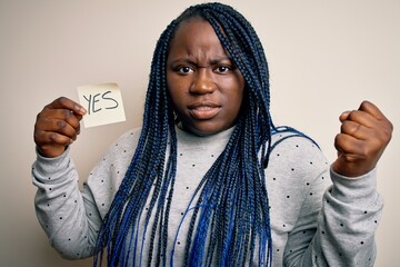 Poster - Young african american plus size woman with braids holding reminder paper with yes message annoyed and frustrated shouting with anger, crazy and yelling with raised hand, anger concept