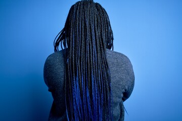 Sticker - African american plus size woman with braids wearing casual sweater over blue background standing backwards looking away with crossed arms