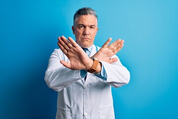 Sticker - Middle age handsome grey-haired doctor man wearing coat and blue stethoscope Rejection expression crossing arms doing negative sign, angry face