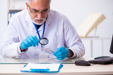 Old male expert criminologist working in the lab for evidence