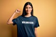 © Krakenimages.com - Young beautiful hispanic woman wearing volunteer t-shirt as social charity moral Strong person showing arm muscle, confident and proud of power