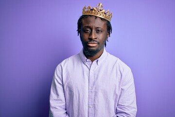 Sticker - Young african american man wearing golden crown of king over isolated purple background depressed and worry for distress, crying angry and afraid. Sad expression.