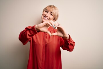 Sticker - Young beautiful business blonde woman with short hair standing over isolated background smiling in love doing heart symbol shape with hands. Romantic concept.