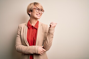 Poster - Young blonde business woman with short hair wearing glasses and elegant jacket smiling with happy face looking and pointing to the side with thumb up.