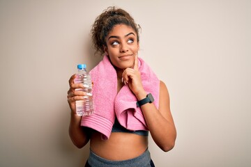 Canvas Print - Young african american sporty woman doing sport wearing towel drinking bottle of water serious face thinking about question, very confused idea