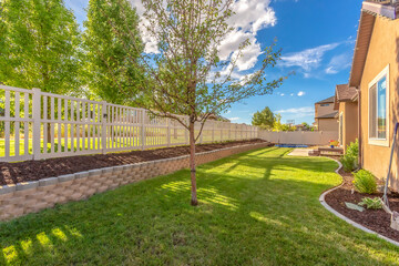 Wall Mural - Home backyard with vibrant lawn and raised planting bed along white picket fence