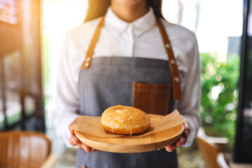 Wall Mural - A waitress holding and serving a piece of homemade donut in wooden tray