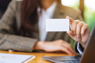 Wall Mural - A businesswoman holding and showing a blank business cards in office