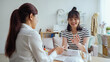 © PRPicturesProduction - Woman in living room apartment receiving manicure by female beautician during home service treatment. young happy girl customer smiling examining her fingers after doing nail varnish polish.