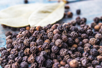 Wall Mural - Black pepper and bay leaves are scattered on blue boards.