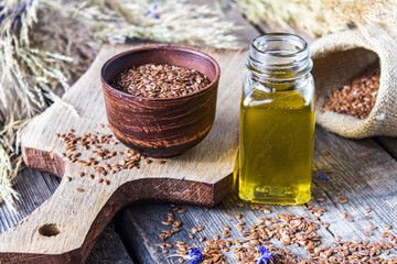 Wall Mural - Flaxseed oil in a jar next to flax seeds on a background of old boards.