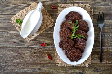 Wall Mural - Tasty homemade liver cutlets on a plate and white sauce. The top view