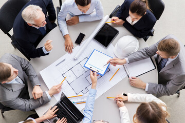 construction business, architecture and building concept - group of architects with blueprint discussing report at office