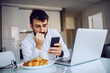 © Dusan Petkovic - Young attractive bearded man getting nervous about message from his boss. he is biting his nails. Morning time, dinning room interior.