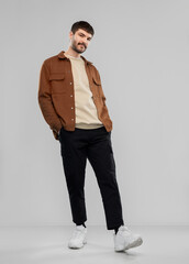 people concept - young man in brown jacket and black pants with mustaches over grey background